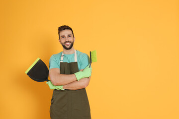 Wall Mural - Man with brush and dustpan on orange background, space for text