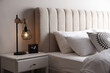 Stylish lamp and alarm clock on bedside table indoors. Bedroom interior elements