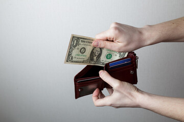 the girl puts one dollar in her wallet. symbol of poverty.