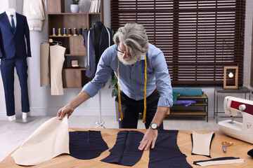 Wall Mural - Professional tailor working with fabric at table in atelier