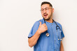 © Asier - Hispanic nurse man isolated on white background points with thumb finger away, laughing and carefree.
