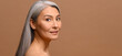 © Vadim Pastuh - Serene middle-aged Asian woman with fresh clean healthy skin isolated on grey. Well-looking mature korean lady looks at camera, small wrinkles near eyes. Anti aging care, natural beauty