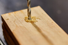 Close up of drilling into wood with screw twisted into place, metal drill bit