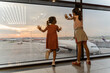 Little sister girls together at the airport waiting for boarding near the big window. Adorable children looks at the planes at the airport. Waiting to leave for a family summer vacation