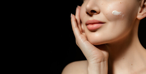skin care. close up beauty portrait of young woman applay cream. isolated on black background, web b