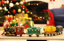 Beautiful Toy Train On Wooden Table Against Blurred Festive Lights. Christmas Celebration