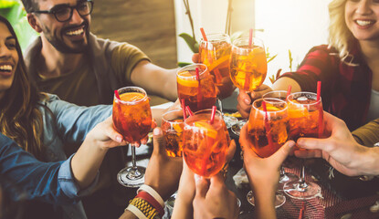 Happy friends cheering drinks glasses in bar restaurant - Young people enjoying happy hour time drinking cocktails - Teenagers celebrating party together - Beverage lifestyle concept