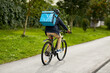 © Syda Productions - food shipping, transportation and people concept - delivery man in bike helmet with thermal insulated bag riding bicycle on city street