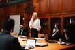 © Maskot - Confident businesswoman discussing with lawyers in board room during conference meeting