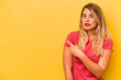 © Asier - Young caucasian woman isolated on yellow background smiling and pointing aside, showing something at blank space.
