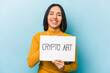 © Asier - Young hispanic woman holding crypto art placard isolated on blue background laughs out loudly keeping hand on chest.