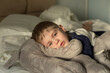 A little boy in pajamas wakes up, lie in bed in the sun s rays. The concept of childhood, health.