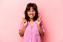 Young Hispanic Woman Isolated On Pink Background Crossing Fingers For Having Luck