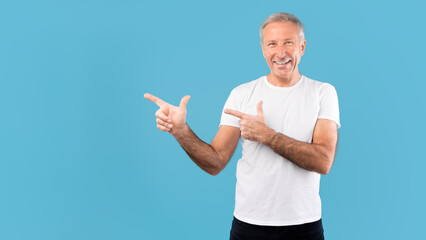 Wall Mural - Excited mature man pointing aside at copy space