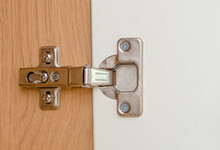 Close Up Of A Concealed Steel Hinge Fitted Into A Kitchen Cabinet