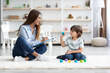 © Prostock-studio - Cute little boy playing with colorful blocks, young professional woman psychologist making notes about mental health