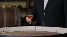 A Man In A Wine Cellar Takes A Glass Of Whiskey In His Hand