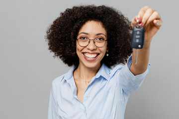 Wall Mural - Close up fun young overjoyed employee business corporate lawyer woman of African American ethnicity in classic formal shirt work in office hold giving car key isolated on grey color background studio