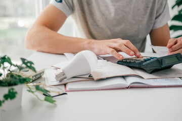 a man counts a bill on a calculator and a check for electricity on the table. payment of utility ser
