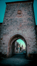 Wide Angle Shot Of Tower With Arch Of A Small French Village, South Of France At Monpazier, Near To The Castles Of Biron - In Background The Tower Of The Church