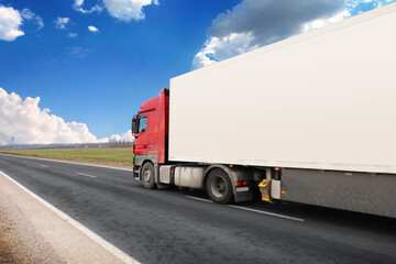 Canvas Print - Truck with a white trailer with blank space for text on a road against a sky with clouds