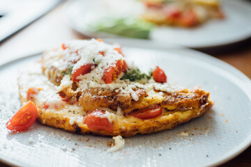 Plate with homemade breakfast: omelet with cheese and tomatoes.