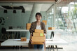 © Natee Meepian - Starting small businesses SME owners female entrepreneurs holding stack of box to review orders online to prepare to pack boxes, sell to customers, online sme business ideas.