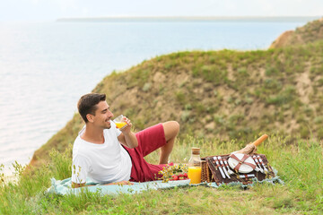 Wall Mural - Handsome young man having picnic in mountains