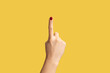 Profile side view closeup of woman hand with red manicure showing number one with finger or showing up side. Indoor studio shot isolated on yellow background.