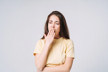 Young Yawning Asian Woman Winner With Long Hair In Yellow Shirt On Grey Background
