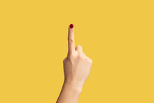 Profile Side View Closeup Of Woman Hand With Red Manicure Showing Number One With Finger Or Showing Up Side. Indoor Studio Shot Isolated On Yellow Background.