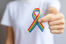 Hand Holding LGBTQ Rainbow Ribbon For Support Lesbian, Gay, Bisexual, Transgender And Queer Community And Pride Month Concept