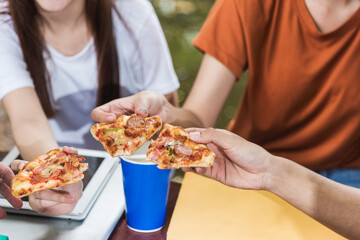 Wall Mural - Students excited woman and man eating pizza together with cheese delicious pizza. they are having fun and enjoy party during lunch at outdoor university, Group friends