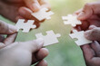 Support, teamwork concept. Close up hands of four businesspeople hold pieces of white puzzle, assemble jigsaw, put it together, joint path to problem solution.