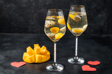 Dessert champagne jelly with exotic fruits - mango and pitahaya in a glass. On a black background