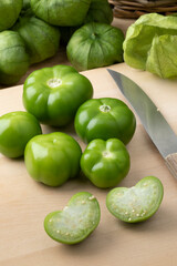 Wall Mural - Fresh green whole and halved Mexican tomatillo on a cutting board close up