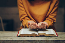 Christian Life Crisis Prayer To God. Praying Hands, Young Woman Prayer With Hands Together Over A Holy Bible, Spiritual Light, Mind, And Soul Peace.
