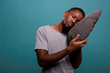 © DC Studio - Tired man using comfortable pillow to get sleepy and take nap over blue background. Exhausted person with insomnia trying to get rest and have peaceful night sleep, bedtime schedule.