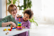 Mother Looking At A Child Playing With An Educational Didactic Toy. Preschool Teacher With A Child Playing With Didactic Toys