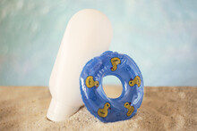 Blank Cosmetics Bottle Staying In Sand With Decorative Swimming Circle Near It.Summer Rest Concept.