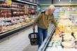 © caftor - elderly man choosing cheese in supermarket