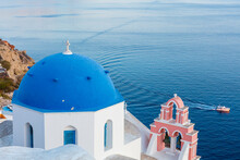 Blue Domed White Church Overlooking Boat In Aegean Sea, Santorini, Cyclades, Greek Islands