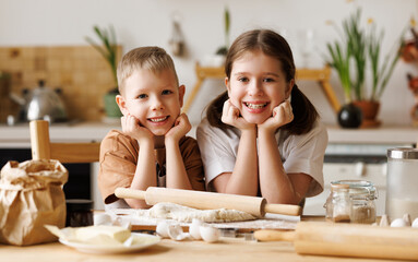 Wall Mural - Happy children brother and sister making dough and cooking together in kitchen