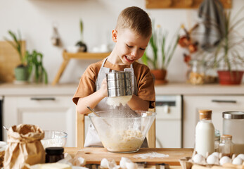 Wall Mural - Happy child boy cooking pastry in kitchen