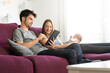 © Marc Calleja - mother and father with their newborn baby on the sofa with a digital tablet