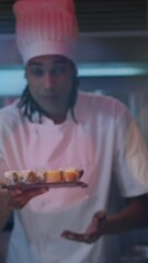 Wall Mural - Animation of sushi text over happy biracial male chef preparing sushi
