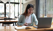 © wichayada - Happy young woman in headphones speaking looking at laptop making notes, girl student talking by video conference call, female teacher trainer tutoring by webcam, online training, e-coaching concept