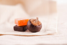 A Chocolate Covered Fig With Two Pieces Of Candy On A Napkin