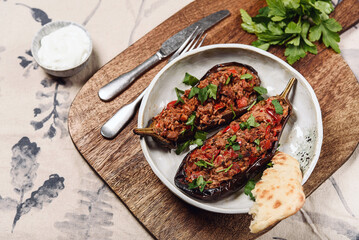 Imam bayildi. Traditional delicious Turkish food: halves of baked eggplant stuffed with vegetables on a plate. Selective focus