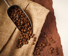 Scoop Of Coffee Beans On Burlap Background